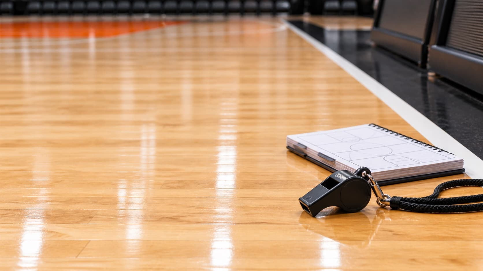 A referee's whistle and notebook on a basketball court